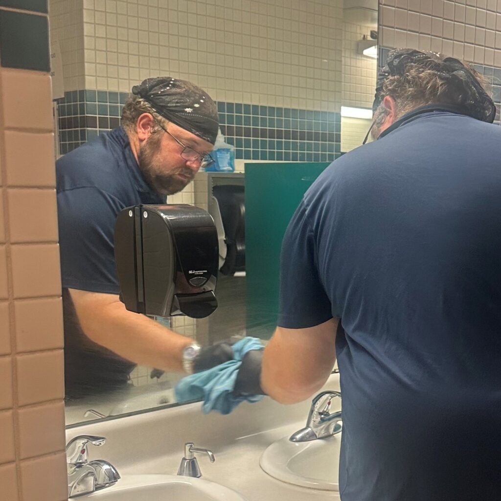 A Liferoots, Inc. employee cleaning a mirror in a restroom