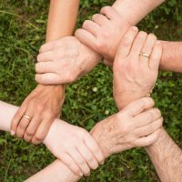 Trust A diverse group of people standing in a circle, holding hands, symbolizing unity and togetherness.