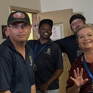 Four Liferoots, Inc. employees smile at the camera, waving hello